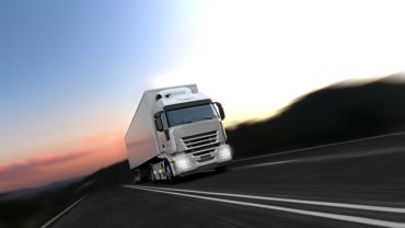 A white truck driving on the highway with the sunset in the background